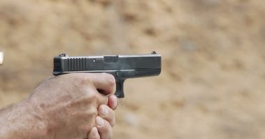 Slow motion of a hand gun firing with cartridge flying away