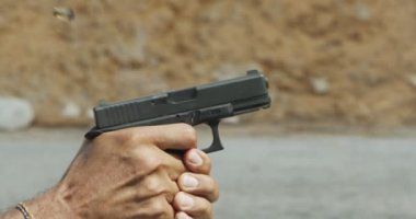 Slow motion of a hand gun firing with cartridge flying away