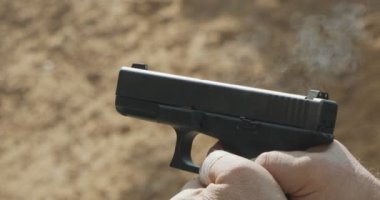 Slow motion of a hand gun firing with cartridge flying away