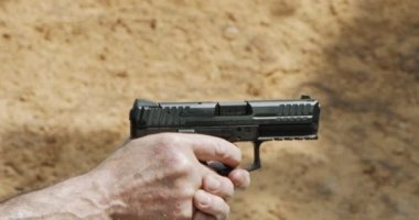 Slow motion of a hand gun firing with cartridge flying away