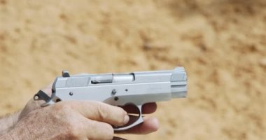 Slow motion of a hand gun firing with cartridge flying away