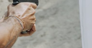 Slow motion close up shot of a man shooting a hand gun while moving