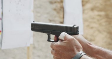 Slow motion close up shot of a man shooting a hand gun while moving