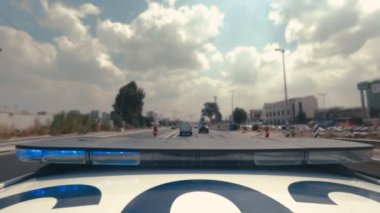 Şehrin sokaklarında mavi ve kırmızı ışıklarla giden polis arabasının zamanı.