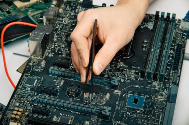 Bir adam elektronik aletleri tamir etmek için bir araç tutar, lehim devre kartını elle monte eder.