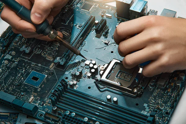 Bir adam elektronik aletleri tamir etmek için bir araç tutar, lehim devre kartını elle monte eder.