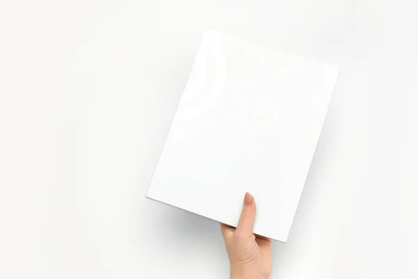 Egy női kéz egy lezárt könyvet tart üres fehér takaróval, fehér alapon.. — Stock Fotó