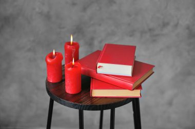 Küçük tahta bir kitap masasında kırmızı kitaplar ve kırmızı mumlar. İç tasarım.