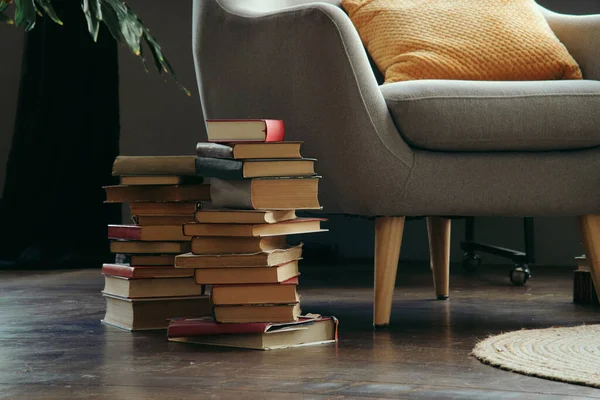 독서용 의자 옆에 있는 낡은 책들 이 바닥에 쌓여 있다. 스톡 이미지