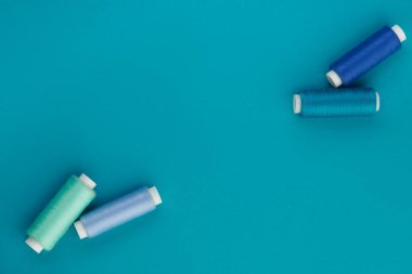 Mavi iplik. Dikiş ipliklerinden oluşan bir set. Mavi arka planda mavinin farklı tonlarında birkaç iplik makarası. Üst görünüm