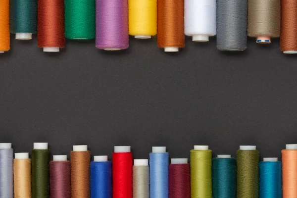 Os fios de costura coloridos são dispostos em um fundo cinza, espaço para texto. — Fotografia de Stock
