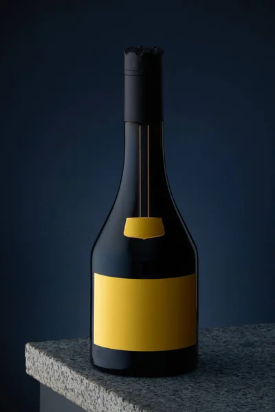 大理石の表面に黄色のラベルと濃い青の背景を持つ高価なアルコール、ウイスキー、コニャック、ブランデーのボトル. — ストック写真