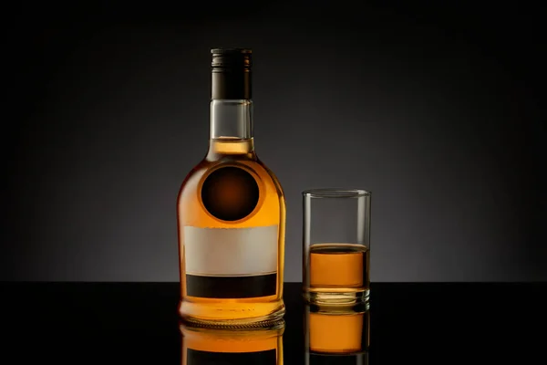 Butelka i szkło z whisky, koniak, brandy na czarnym tle. — Zdjęcie stockowe