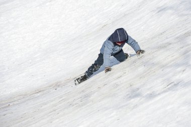 Çocuk kaygan kar kayağına tırmanmaya çalışıyor ama yine de düşüyor ve iniyor..