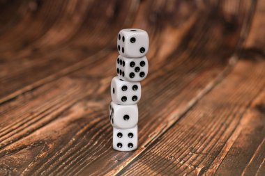 Tahta bir dokuda üst üste yığılmış beyaz zarlar. Kumarhane ve kumar kavramı.