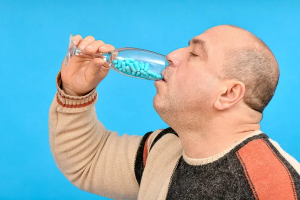 ブルーの薬用カプセルが入ったシャンパングラスから男が飲む — ストック写真