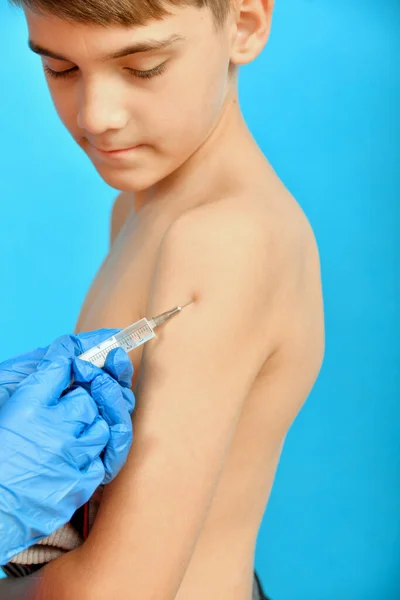 戴防护手套的医生给孩子接种疫苗 在一个青少年的肩上注射毒品 — 图库照片