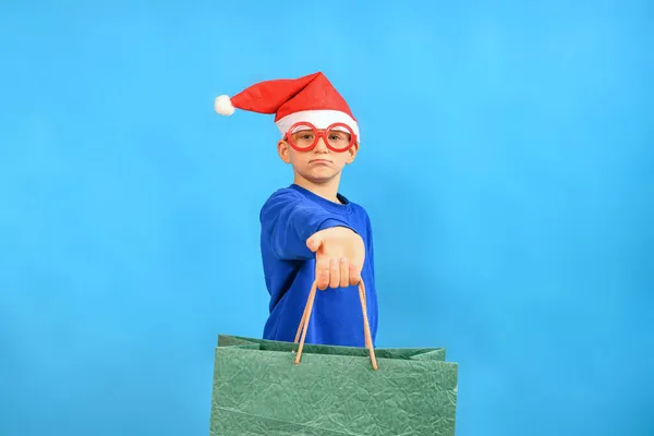 Veselý Chlapec Klobouku Santa Claus Ukazuje Dárkové Tašky Vánoce — Stock fotografie