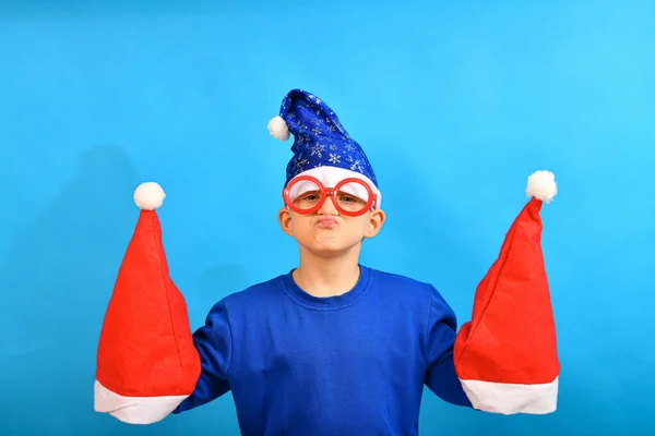 Legrační Chlapec Modrém Klobouku Santa Claus Drží Červené Klobouky Nový — Stock fotografie