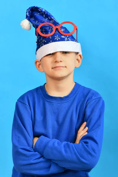 Rolig Pojke Blå Jultomte Hatt Och Röda Glasögon Huvudet Korsade — Stockfoto
