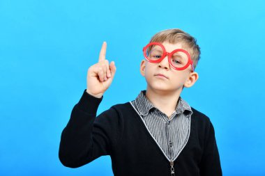 Kırmızı gözlüklü zeki bir çocuk işaret parmağını yukarı kaldırdı..
