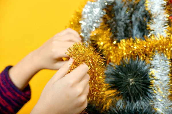 男の子はクリスマスツリーを新年のおもちゃやきらびやかなティンセルで飾ります — ストック写真