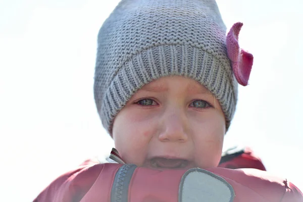 子供は通りで泣いている 帽子を被った少女と目に涙を浮かべた赤いジャケット — ストック写真