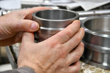 Bir işçi, tam doğruluğunu ölçmek ve kontrol etmek için cnc makinesinden sonra kolu tutar.