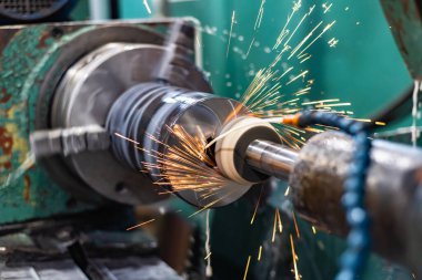 Uçan kıvılcımlar ve su soğutuculu öğütme makinesinin dış yüzeyindeki metalin yüksek hassasiyetli mekanizması..