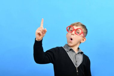 Kırmızı gözlüklü zeki bir çocuk işaret parmağını yukarı kaldırdı..