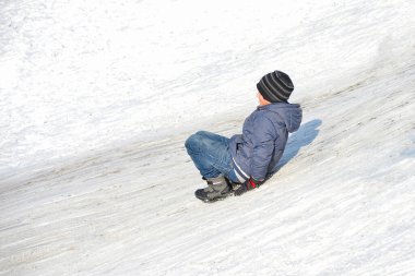 Çocuklar kışın oynar, kar kaydırağında yukarı aşağı giderler..