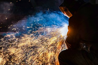 Kaynakçı grafit karbon elektrot ile keser. Kıvılcımlar uçar gider.