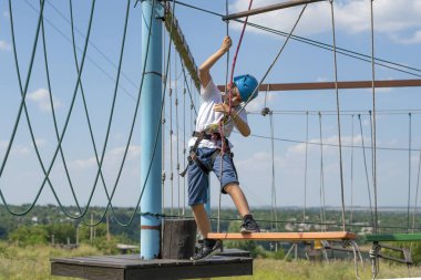 Bir sporcu çocuk, aşırı parktaki bir ip yolda engelleri aşıyor..