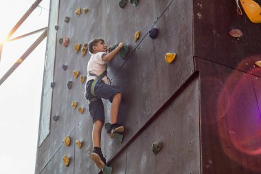 Bir çocuk bir spor parkının duvarına tırmanıyor..