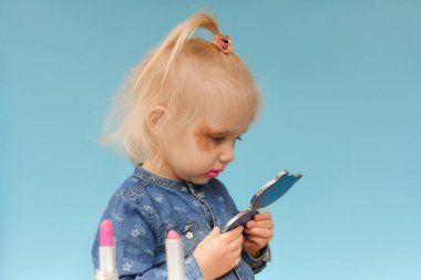 Beceriksizce ebeveyn makyajı yaptıktan sonra çocuk aynada kendine bakar..