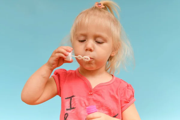 Маленькая Девочка Надувает Мыльные Пузыри Голубом Фоне — стоковое фото