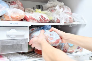 Genç bir adam mikrodalgada yemek hazırlamak için dondurucudan uygun yiyecekleri alır..