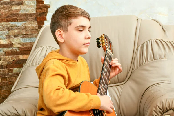 Αγόρι Κάθεται Σπίτι Μια Δερμάτινη Πολυθρόνα Και Παίζει Κιθάρα Έξι — Φωτογραφία Αρχείου