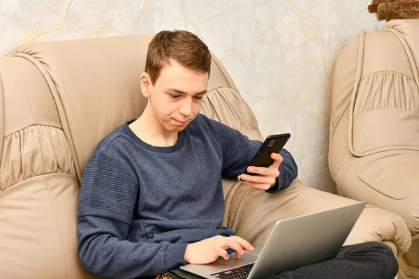 Genç Bir Adam Dizüstü Bilgisayarla Meşgul Elinde Bir Telefon Tutuyor — Stok fotoğraf