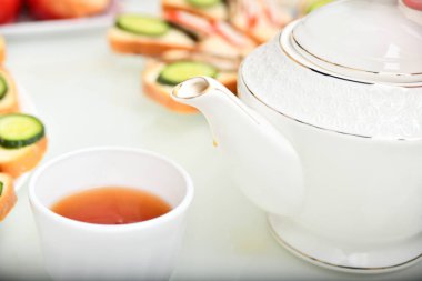 Masadaki mutfakta çay ve çaydanlık olan beyaz bir fincan..