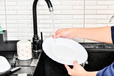 Ev sahibesi kadın bulaşıkları musluk suyuyla yıkıyor..