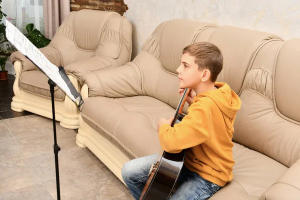 Chico Está Aprendiendo Tocar Guitarra Delante Las Notas Enseñando Música — Foto de Stock