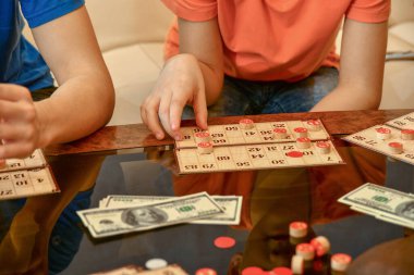 Piyango kartları, fişler ve para cam sehpanın üzerinde. İnsanlar para için loto oynar..