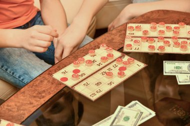 Piyango kartları, fişler ve para cam sehpanın üzerinde. İnsanlar para için loto oynar..