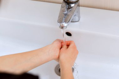 Çocuk ellerini musluk suyuyla yıkıyor..