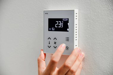 The woman controls the temperature in the house. Air conditioning and heating system in a private house.