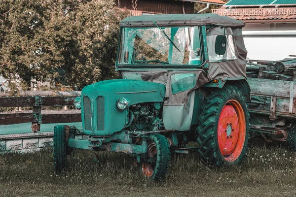 An old tractor with various garbage stands in the yard in the village.