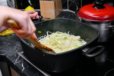 Mutfakta bir kadın tencerede lahana pişiriyor..