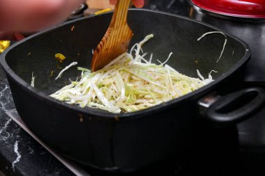 Genç yeşil lahana, mutfaktaki tavada pişiyor..