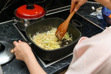 Mutfakta bir kadın tencerede lahana pişiriyor..